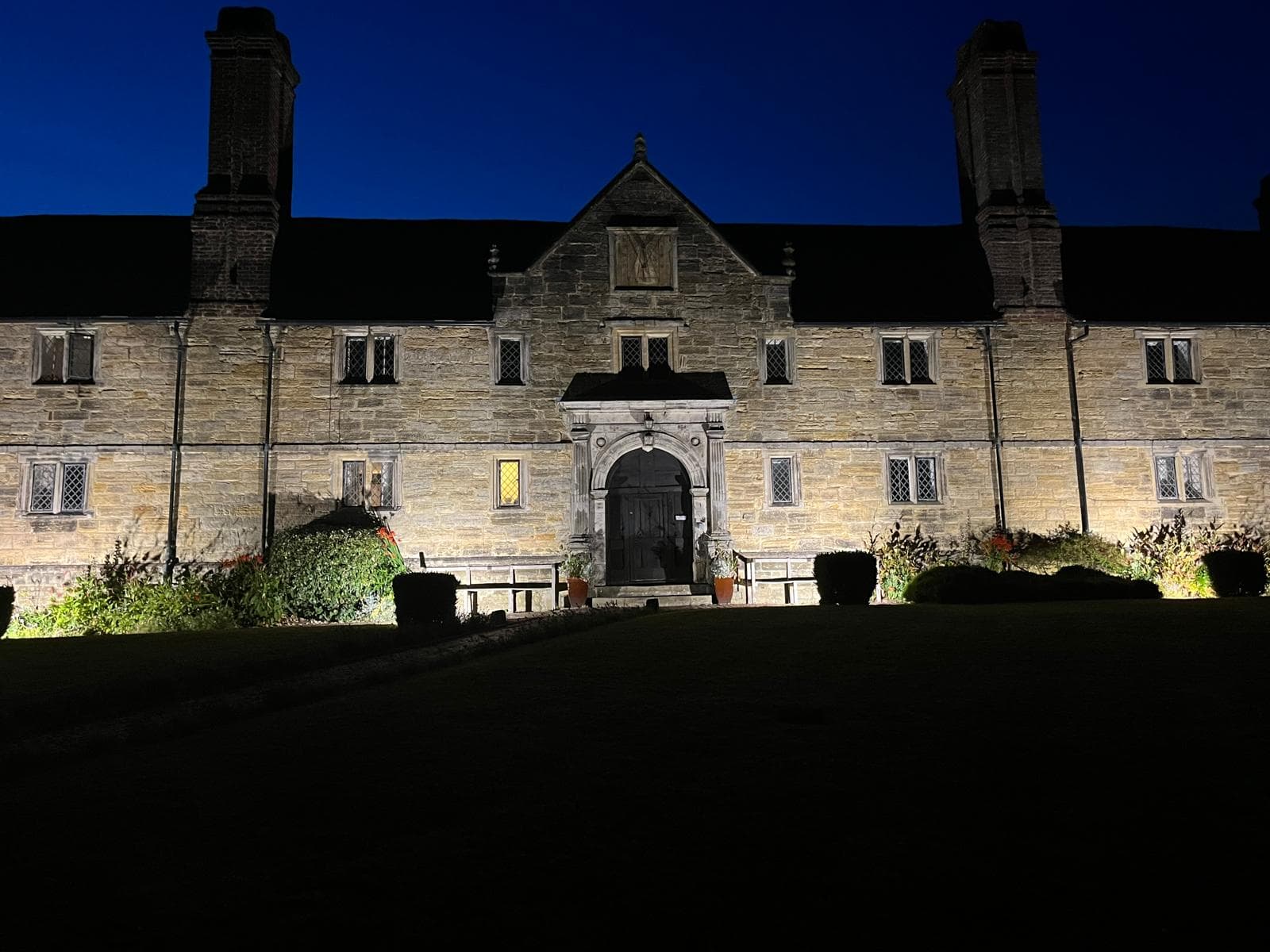 A Grade II listed building photographed at dusk with warm architectural uplighters highlighting the stone facade and main entrance.
