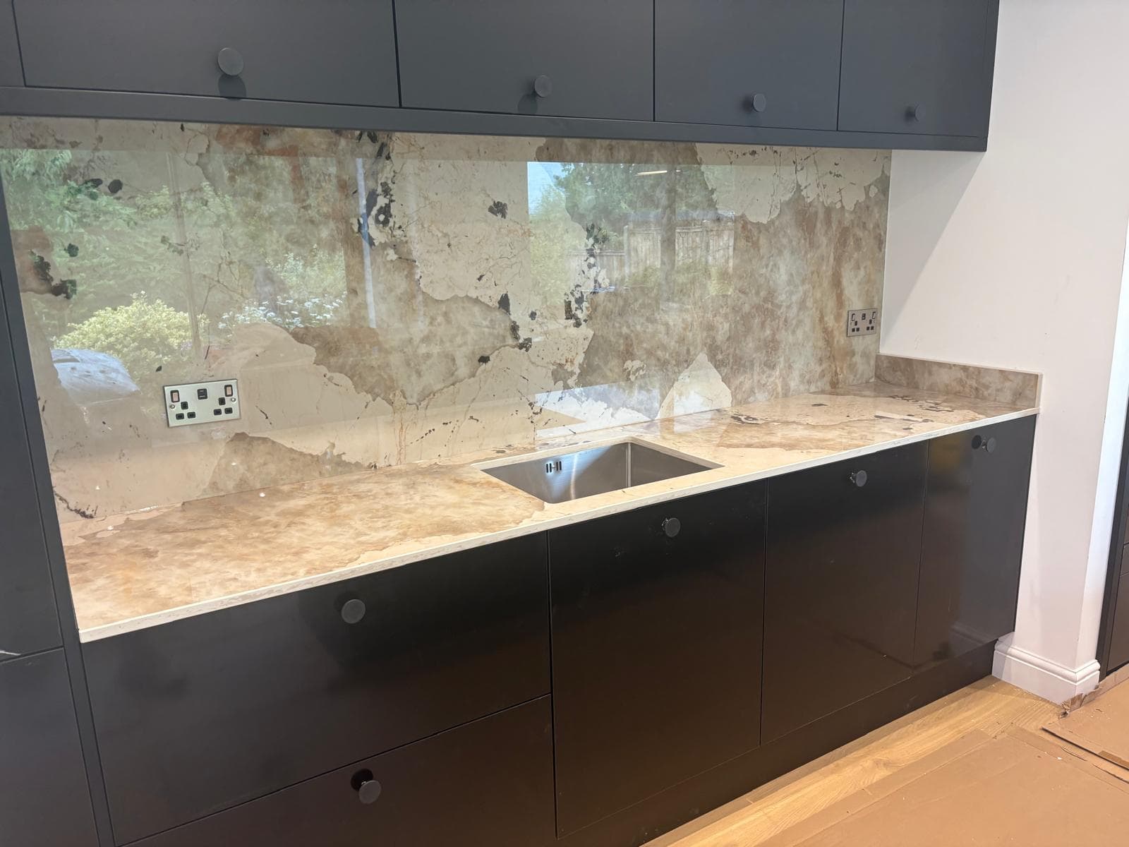Wide view of a finished luxury kitchen with recessed LED downlights, integrated appliance lighting, and matching brass sockets along the worktop.
